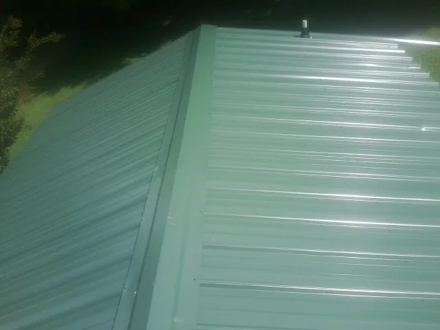 New green metal panels meeting at the ridge of a roof — Flat Roof Repair work by our crew in Dora