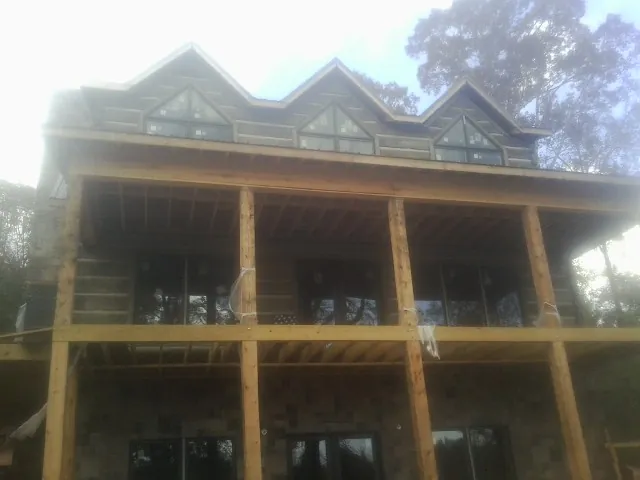 Dormers and porch framing on a large log home under construction — Roof Coating work by our crew in Dora