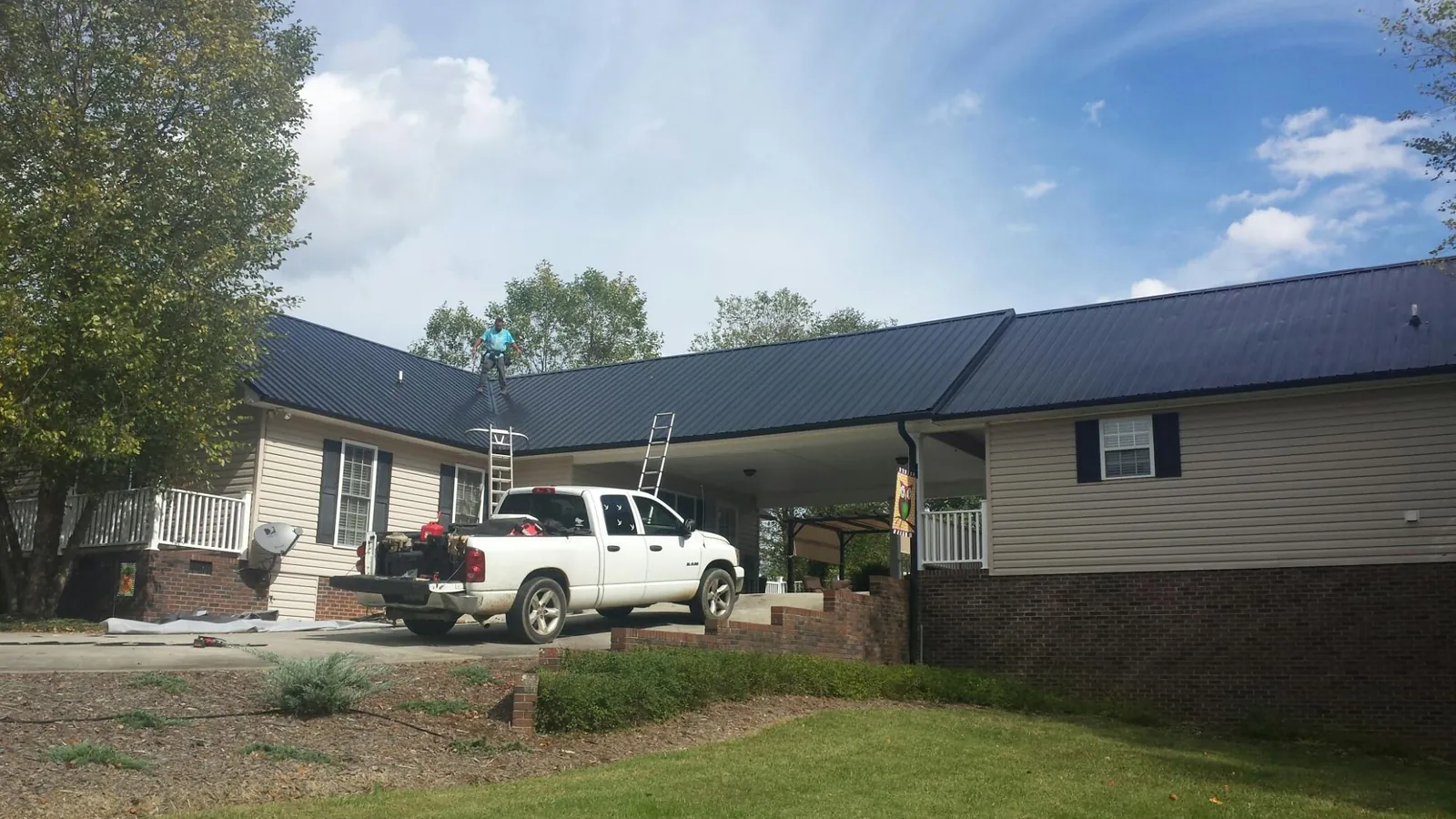 Black metal roof over a home and attached breezeway with ladders set in Dora