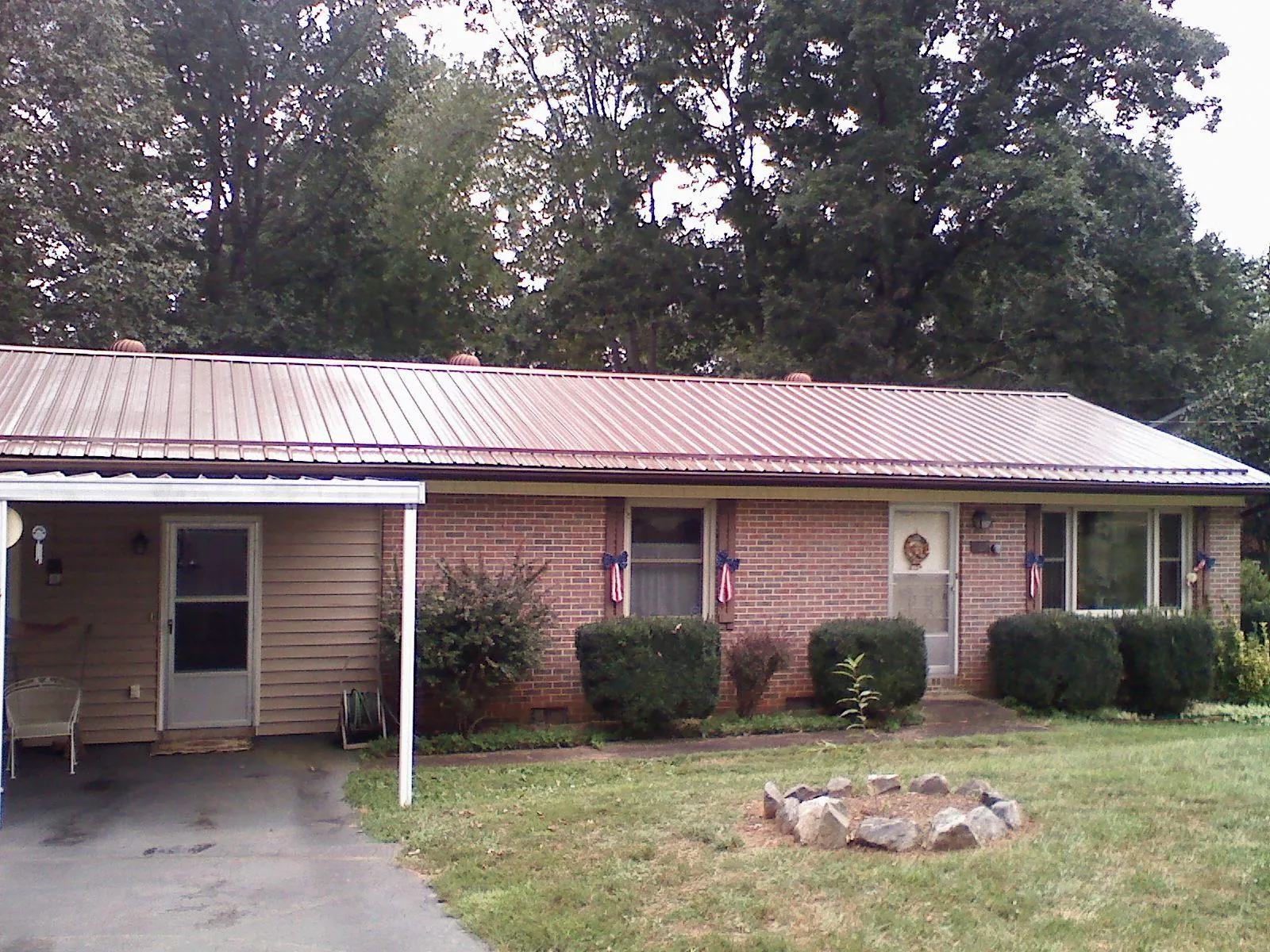Bronze metal roof and carport on a brick ranch home — Roof Repair work by our crew in Dora