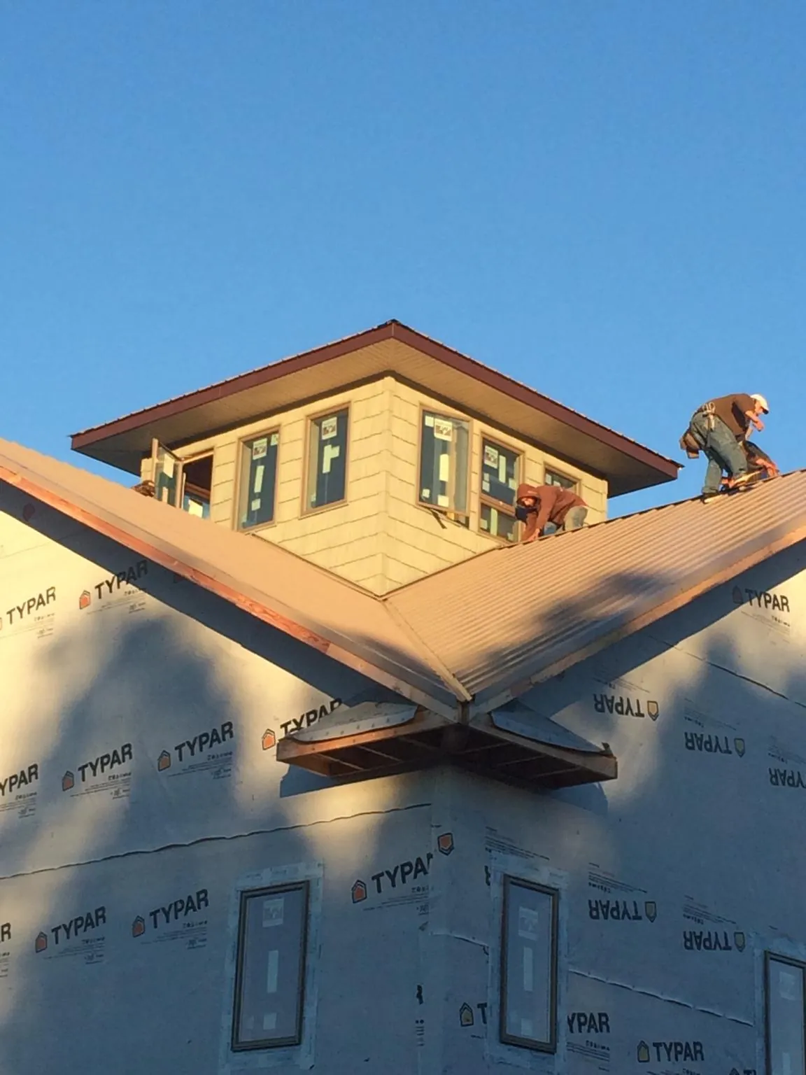 Roofers working around a rooftop cupola on a new metal roof at sunset — Roof Waterproofing in Dora by Roofing Brothers